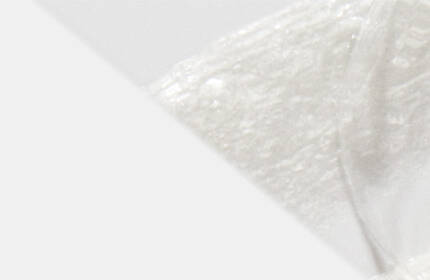A close-up view of a smooth, white substance, possibly cream or a similar texture, against a light background.
