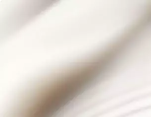 Tessuto bianco morbido e fluente, con pieghe delicate che creano un effetto di movimento.