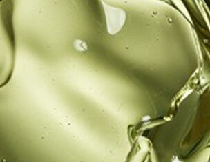 Liquido d&apo;olio verde chiaro che si muove e crea riflessi, evidenziando la sua consistenza viscosa.