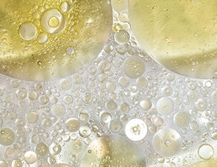 Macchia di cerchi e bolle di olio su superficie trasparente, creando un effetto visivo risplendente e astratto.