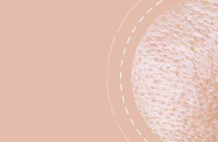 Close-up of textured skin with a soft, peach-colored background.