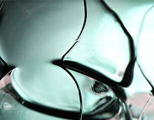 Close-up of smooth, translucent glass fragments showcasing fluid shapes and reflections in soft light.