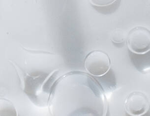 Persone gocce d'acqua su una superficie bianca, creando riflessi e trasparenze.