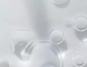 Persone gocce d'acqua su una superficie bianca, creando riflessi e trasparenze.