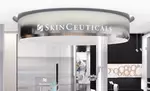 Insegna in metallo del marchio SkinCeuticals all\'interno di un elegante centro estetico moderno.