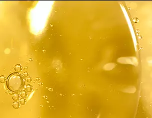 Dettaglio di un liquido giallo con bolle d'aria che galleggiano in superficie, creando un effetto luminoso e trasparente.