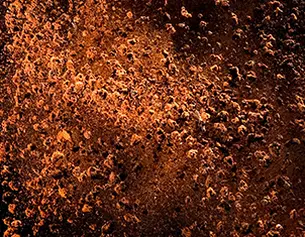 Superficie irregolare in tonalita di marrone e arancione, con texture che ricordano ruggine e imperfezioni naturali.