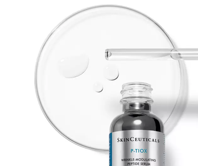 Flacone di siero wrinkle-modulating P-TIOX di SkinCeuticals accanto a una piastra di Petri con gocce di prodotto.