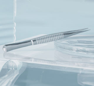 A close-up of a minimalist surgical or dental setting featuring a sleek, metallic tweezer resting on a clear surface, with soft lighting creating a calm atmosphere.