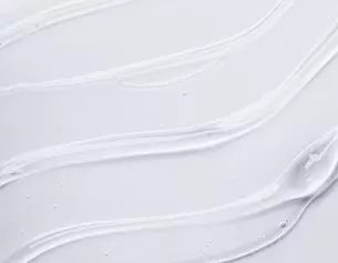 A smooth, white cream or gel smeared on a light background, with flowing textures and glossy highlights.