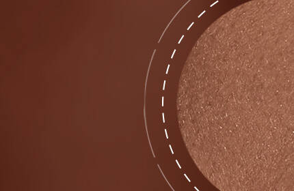 A close-up image of a smooth, shimmery bronze surface with a circular accent highlighting its texture.