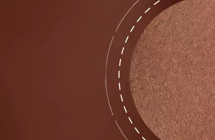 A close-up image of a smooth, shimmery bronze surface with a circular accent highlighting its texture.