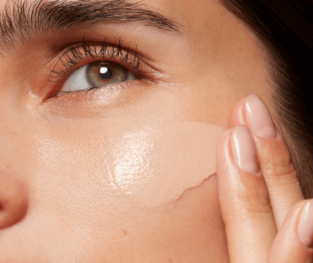 Una persona applica un fondotinta sulla pelle del viso, evidenziando l'attenzione alla bellezza e alla cura della pelle.