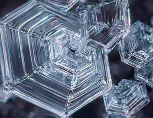 Close-up of intricate, hexagonal ice crystals sparkling against a dark background.