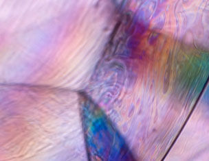 Abstract close-up of colorful, iridescent patterns resembling the surface of a soap bubble or oil slick.