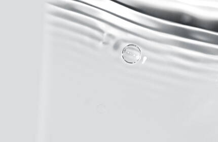 A close-up of smooth water with gentle ripples and light reflections, creating a tranquil and serene atmosphere.
