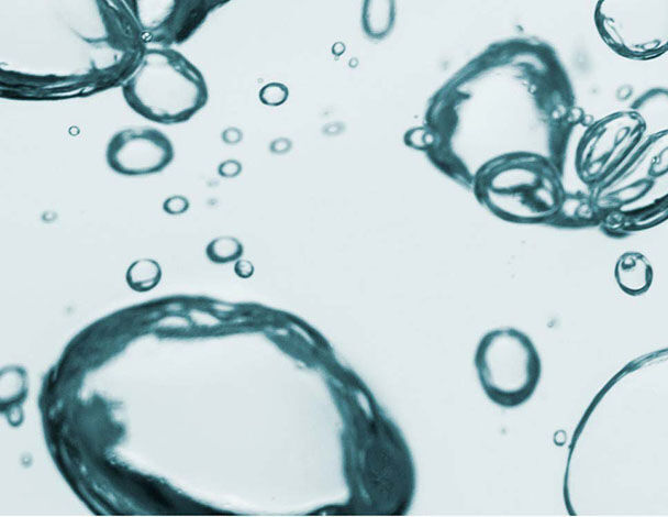 Bollicine d'aria in acqua, con diverse forme e dimensioni che galleggiano su uno sfondo chiaro.