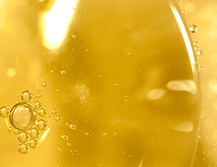 Primo piano di bolle d'aria in un liquido giallo dorato, con riflessi luminosi e texture fluida.