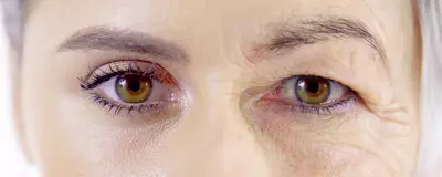 Due occhi di una donna, uno con trucco e l'altro senza, evidenziando differenze di eta e aspetto.