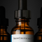 Tre flaconi contagocce ambrati, quello centrale con etichetta "SkinCeuticals", su sfondo scuro