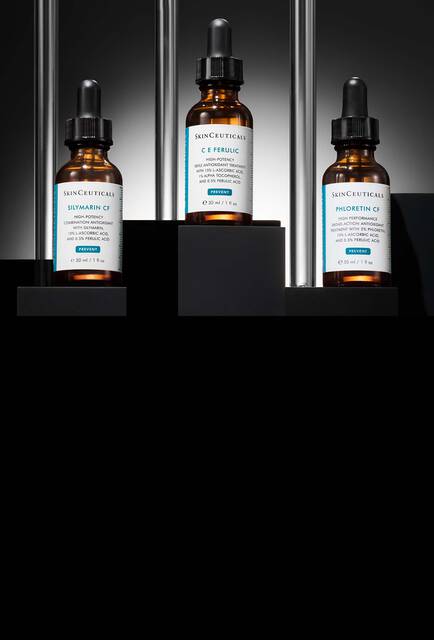 Una collezione di prodotti Skinceuticals, inclusi A.G.E. Interrupter Ultra Serum, HA Intensifier Multi-Glycan, P-TIOX e Advanced RGN 6, esposti su blocchi trasparenti contro uno sfondo scuro e scintillante con effetto bokeh