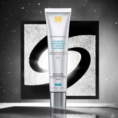 Una bottiglia di protezione solare Advanced Brightening UV Defense davanti a uno sfondo nero e argento con il logo Skinceuticals.