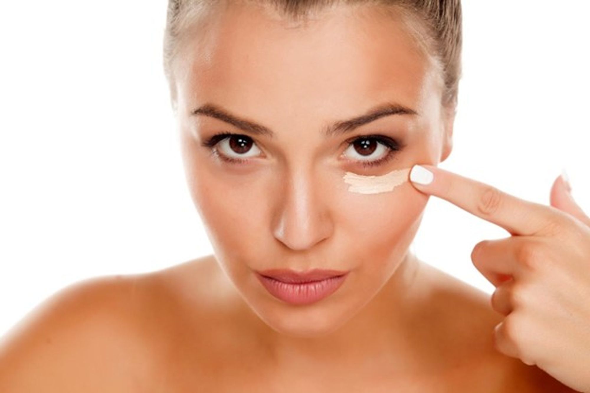 Una donna applica il correttore sotto l'occhio, apparendo sicura e concentrata.